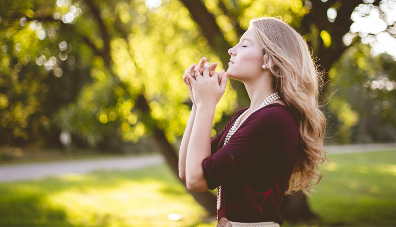 Woman with clasped hands making the gesture of prayer.