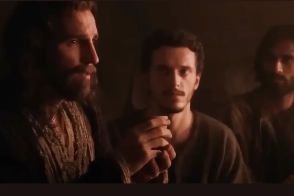 Scene from the film "The Passion of the Christ" showing Jesus at the Last Supper, holding the bread as he institutes the Eucharist, with his disciples silently watching.