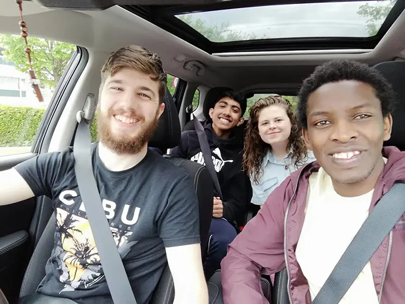 Samuel de adolescente, sonrie junto a tres amigos un coche durante el NET en Irlanda.